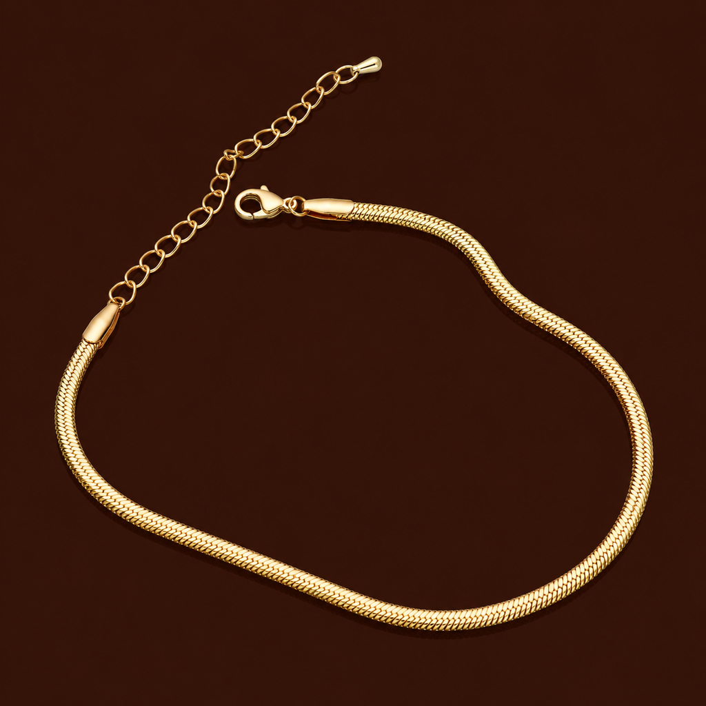 Ari Anklet gold snake chain herringbone anklet on dark background – minimal flat chain stainless steel anklet for women, non-tarnish and hypoallergenic