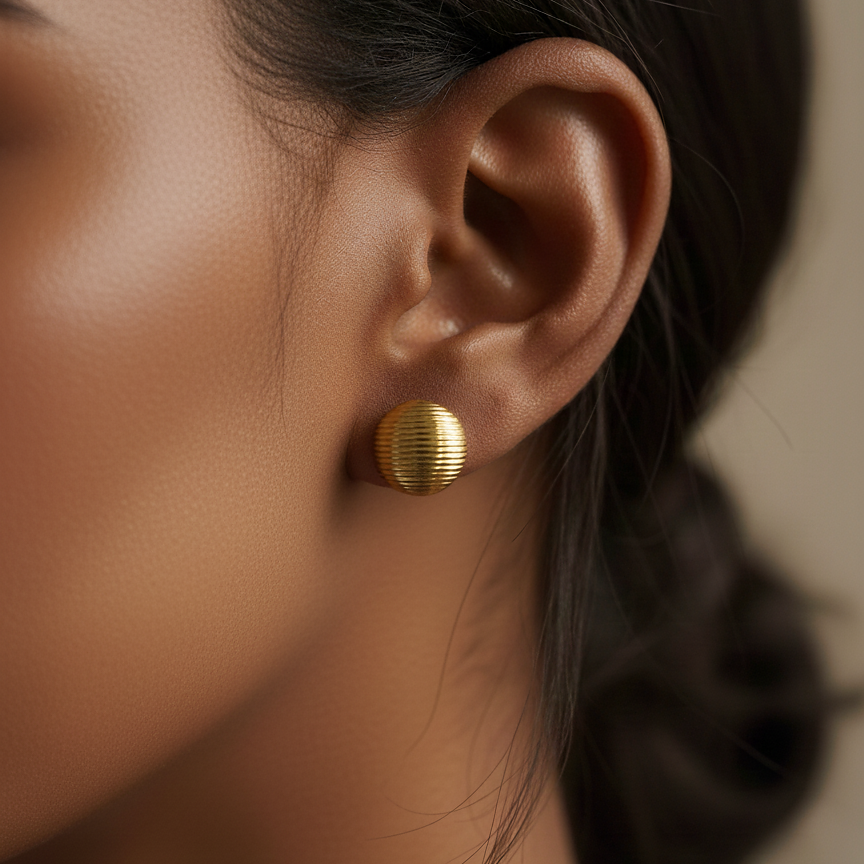 Ava Studs gold ribbed dome button earrings worn on ear in editorial sunlight portrait – minimalist hypoallergenic stainless steel stud earrings, non tarnish and waterproof