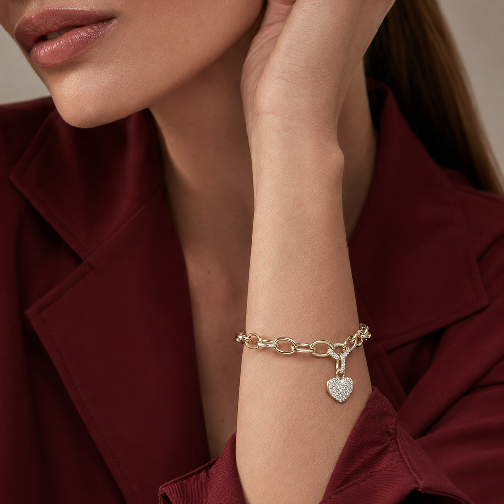 Bella Bracelet gold heart charm bracelet worn on wrist with red blazer – pavé cubic zirconia heart charm on gold link chain, waterproof non-tarnish hypoallergenic women's bracelet
