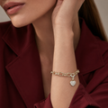 Bella Bracelet gold heart charm bracelet worn on wrist with red blazer – pavé cubic zirconia heart charm on gold link chain, waterproof non-tarnish hypoallergenic women's bracelet