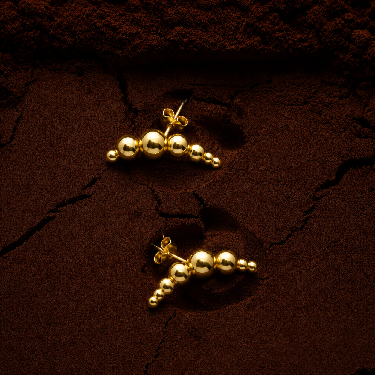 Bibi Studs graduated polished gold ball stud earrings with five spheres in ascending size on dark textured background – hypoallergenic non-tarnish waterproof stainless steel gold stud earrings
