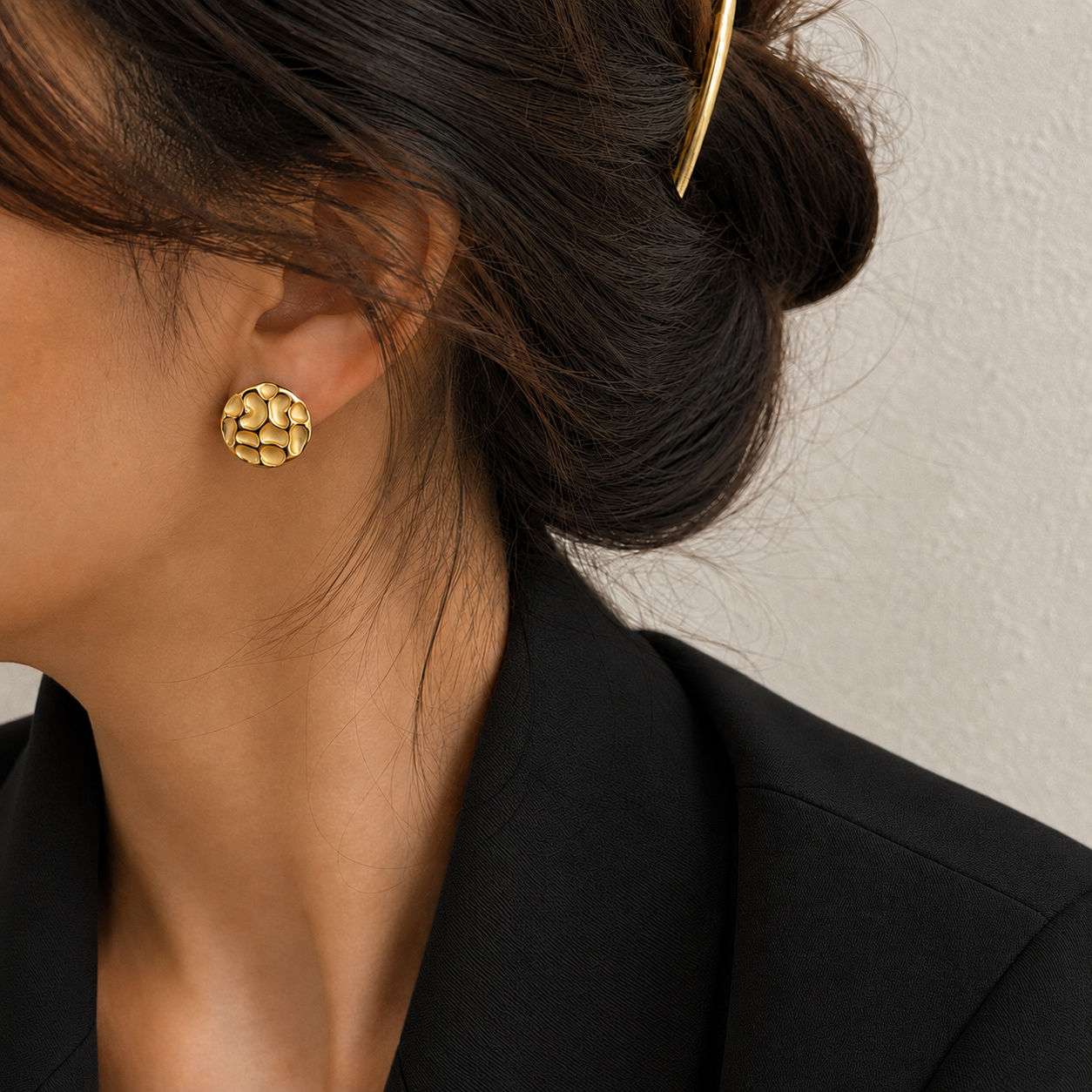Chrysa Studs textured circular gold disc stud earrings with hammered cobblestone surface on a lightskinned model – hypoallergenic 316L stainless steel, tarnish-free and nickel-free for everyday and going-out wear