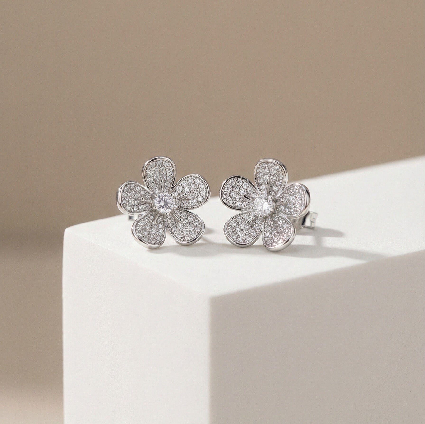 Daeze Studs silver pavé cubic zirconia flower stud earrings with CZ solitaire centre on white display block – surgical steel sparkle earrings for sensitive ears that don't tarnish