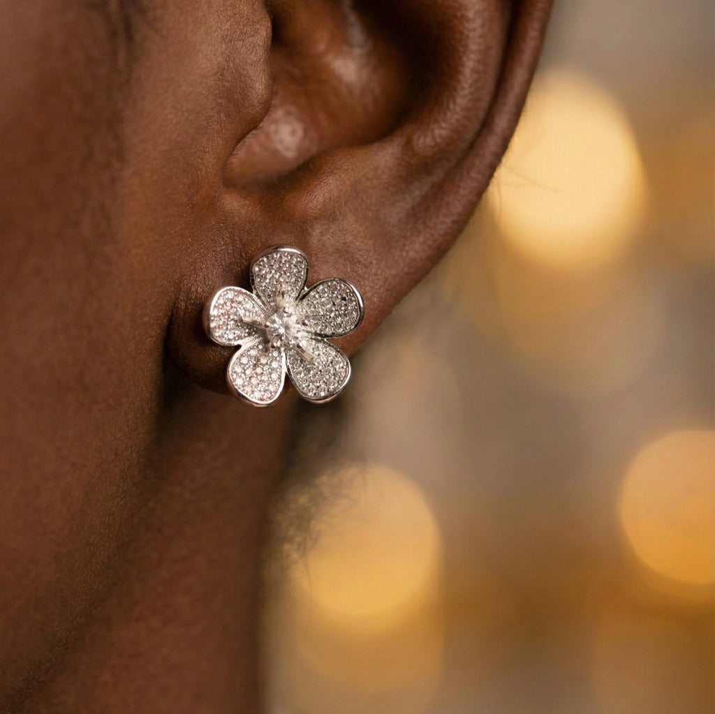 Daeze Studs silver pavé CZ flower stud earrings with cubic zirconia petals and solitaire centre worn by model against golden bokeh background – surgical steel sparkle earrings for sensitive ears