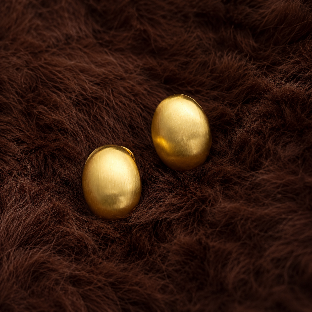 Demi Studs gold oval dome stud earrings resting on brown textured surface – waterproof non-tarnish stainless steel earrings for sensitive ears