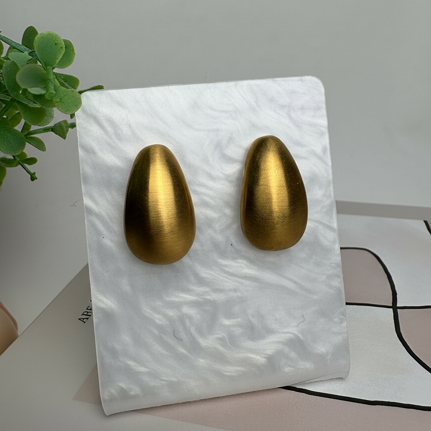 Elara Studs chunky brushed gold teardrop earrings displayed on white marble stand with greenery – hypoallergenic non-tarnish stainless steel dome earrings capsule jewellery