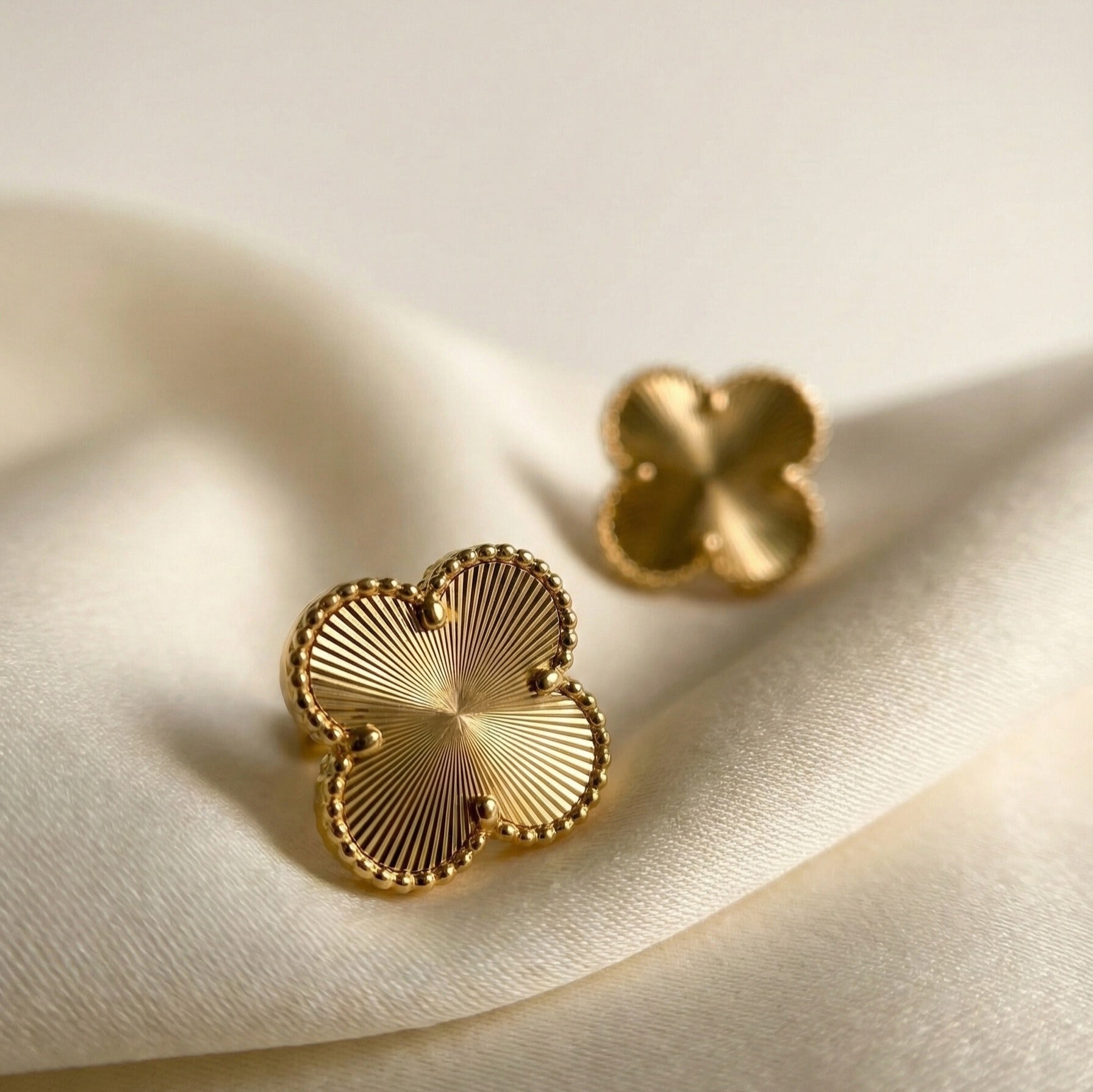 Eva Studs gold clover stud earrings with radiating guilloché sunburst engraving and beaded border on ivory silk – tarnish-free waterproof stainless steel earrings for sensitive ears