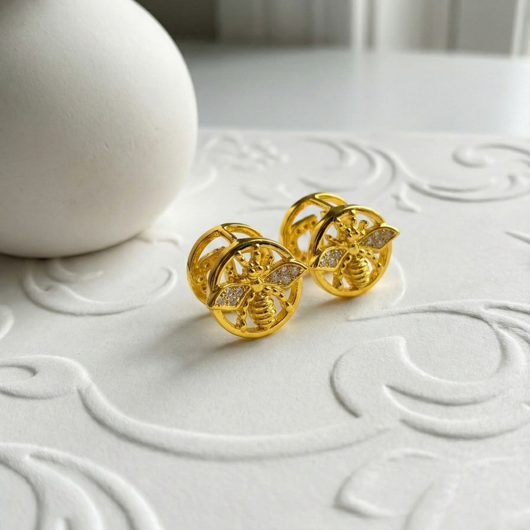 Kamsee Studs gold bee stud earrings with CZ crystal wings and ridged gold body inside circular frame – water resistant surgical steel cubic zirconia earrings for ladies