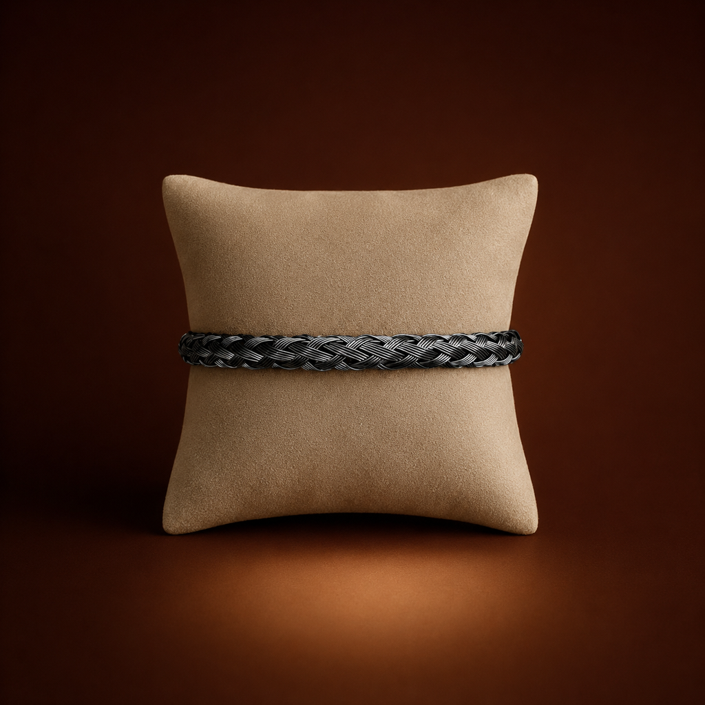 Koa Bracelet black braided woven bangle on cushion display – bold stretch stainless steel bangle, non-tarnish waterproof hypoallergenic UK jewellery