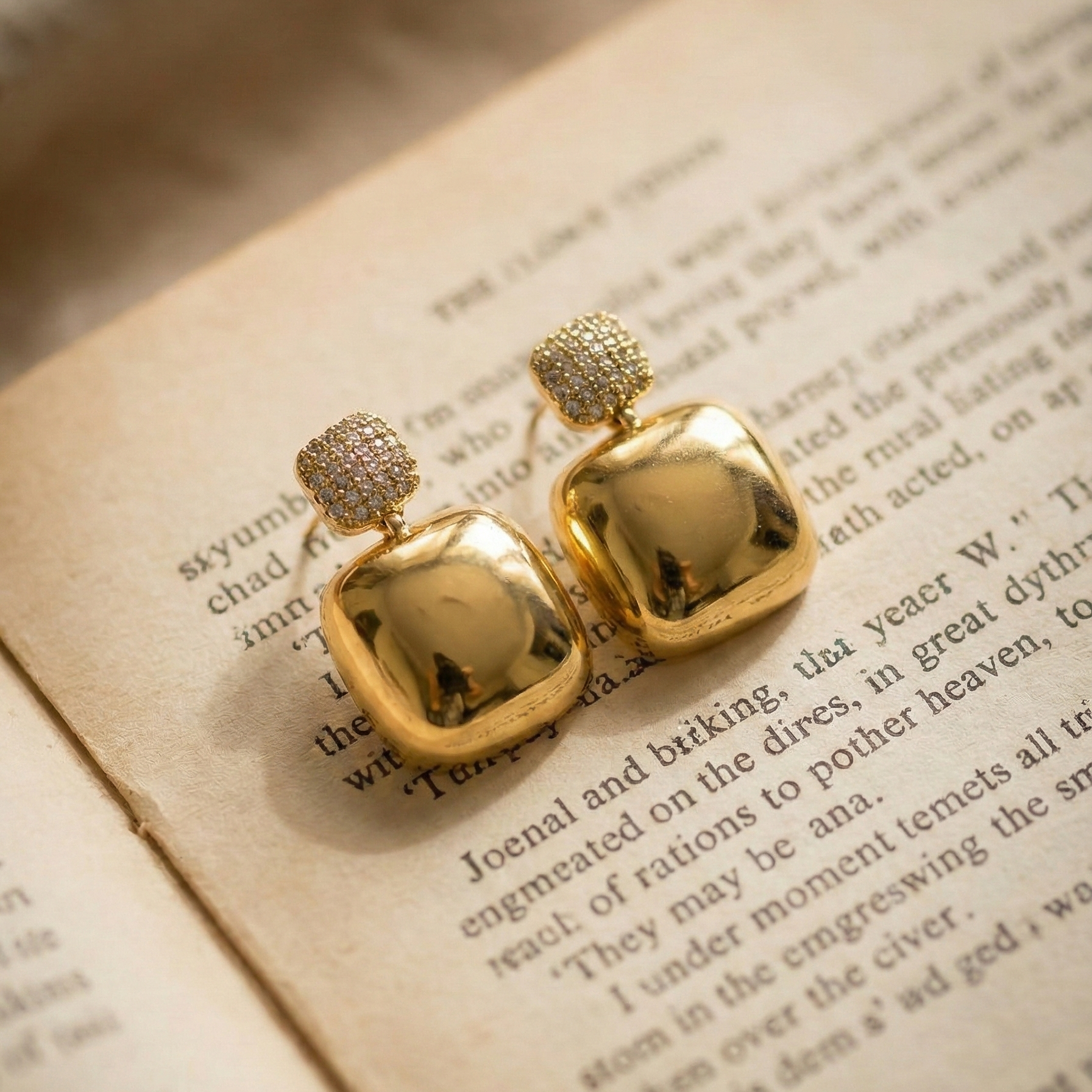 Nanya Drops gold drop earrings with pavé cz top and chunky square gold drop on open book page – sparkle non-tarnish stainless steel cubic zirconia earrings