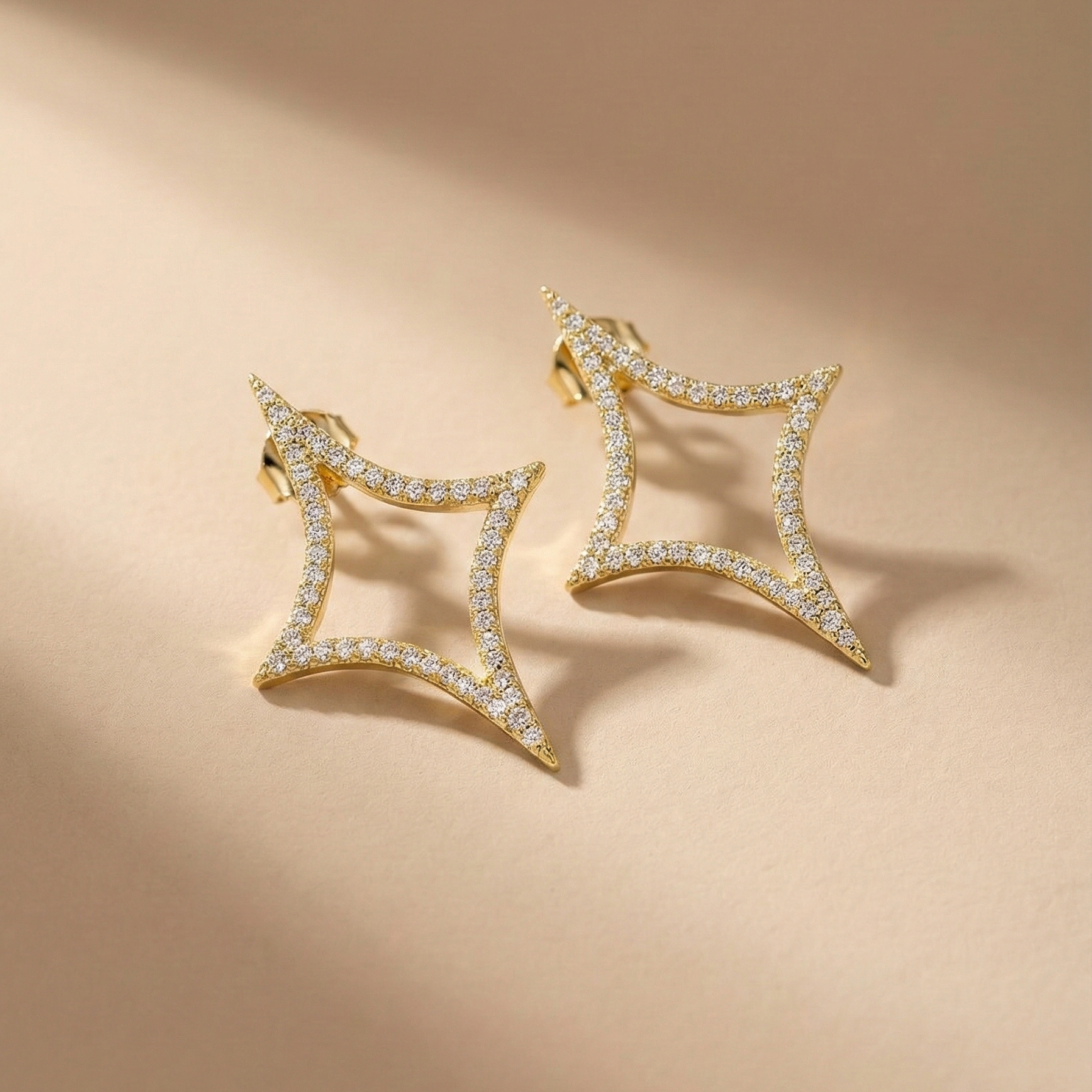 Nova Studs gold pavé sparkle star stud earrings on beige background – cubic zirconia statement stud earrings in tarnish free waterproof surgical steel