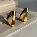 Nysa Studs brushed gold ribbon earrings with twisted asymmetric fold worn by model with braided hair – hypoallergenic stainless steel gold statement earrings