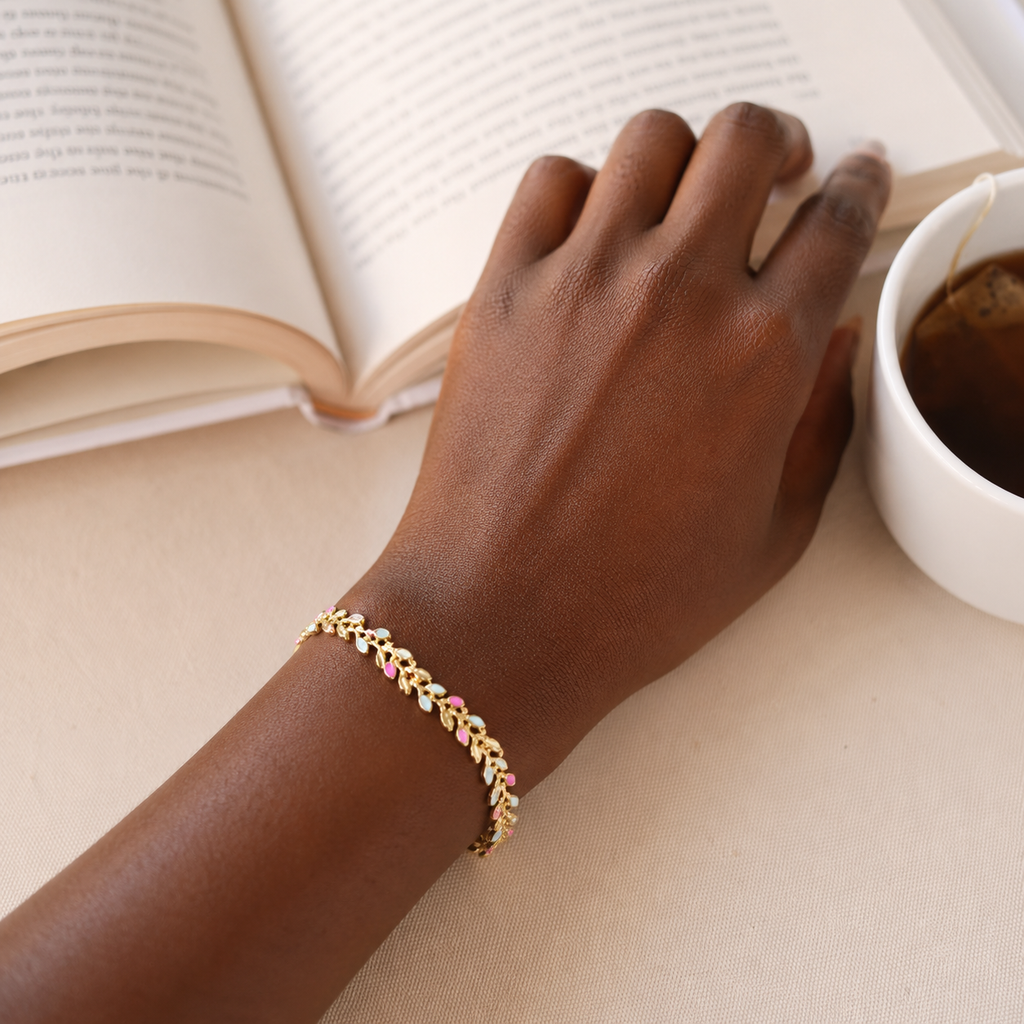 Petra Bracelet pink and blue enamel gold leaf bracelet worn on wrist beside book and coffee – stackable adjustable women's chain bracelet, waterproof hypoallergenic UK jewellery