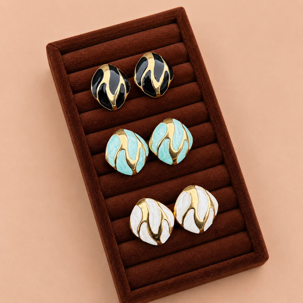 Riva Studs enamel swirl oval stud earrings in black and gold, mint green and gold, and white and gold displayed in dark velvet jewellery box – hypoallergenic non-tarnish stainless steel everyday earrings