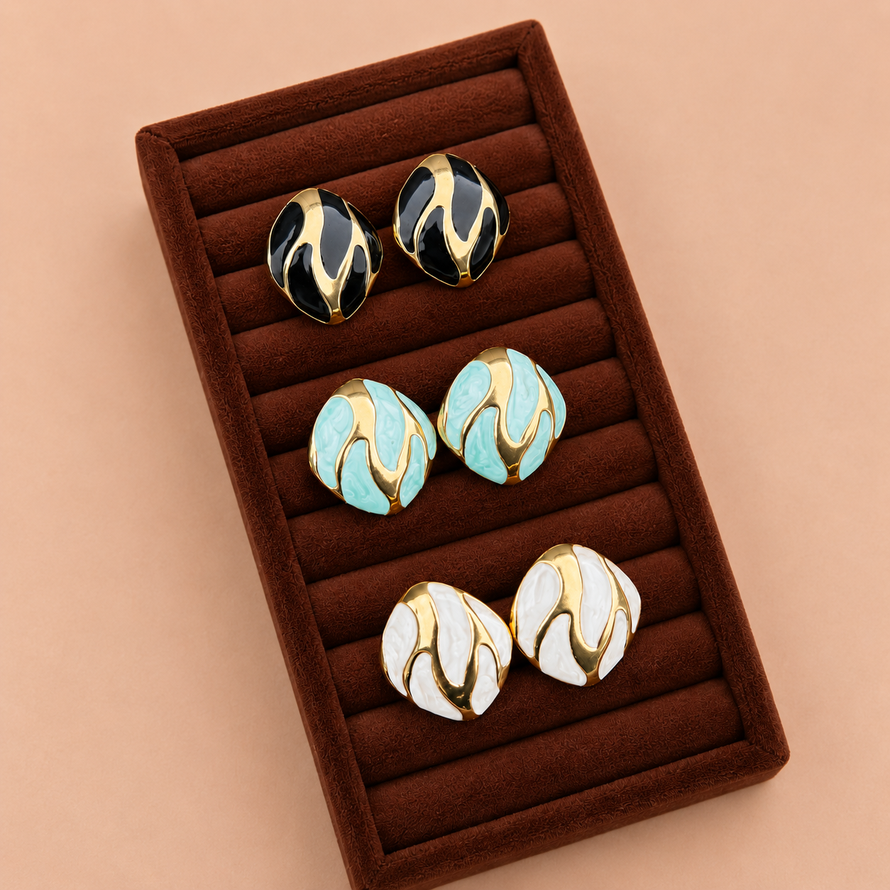 Riva Studs enamel swirl oval stud earrings in black and gold, mint green and gold, and white and gold displayed in dark velvet jewellery box – hypoallergenic non-tarnish stainless steel everyday earrings