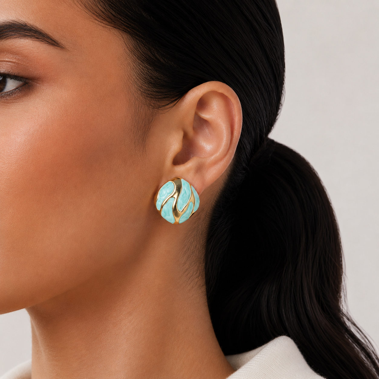 Riva Studs mint green and gold enamel swirl oval stud earrings with bold wave detail – hypoallergenic nickel-free stainless steel non-tarnish earrings for sensitive ears styled on a lightskinned model 