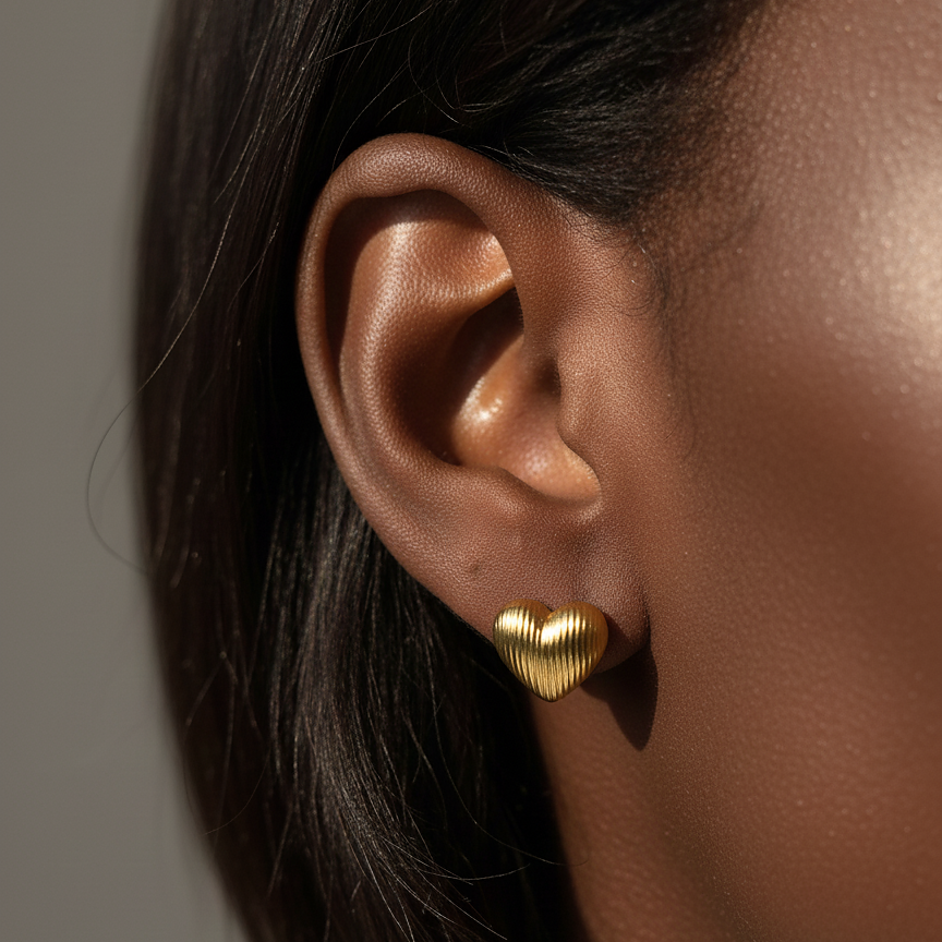 Ugo Studs gold fluted heart stud earrings worn on ear in editorial close-up – minimalist gold heart earrings in non-tarnish surgical steel stud earrings for women