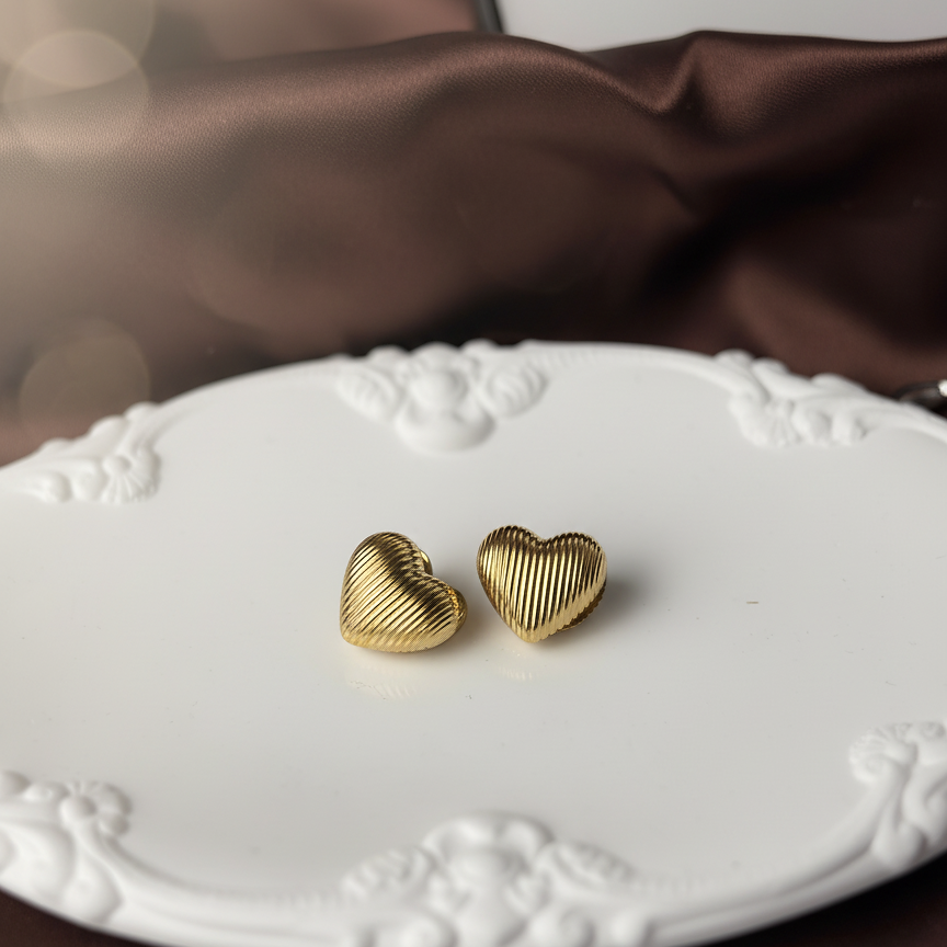 Ugo Studs gold ribbed heart stud earrings on ornate vintage white plate with dark satin – fluted gold heart earrings in non-tarnish gold waterproof stainless steel
