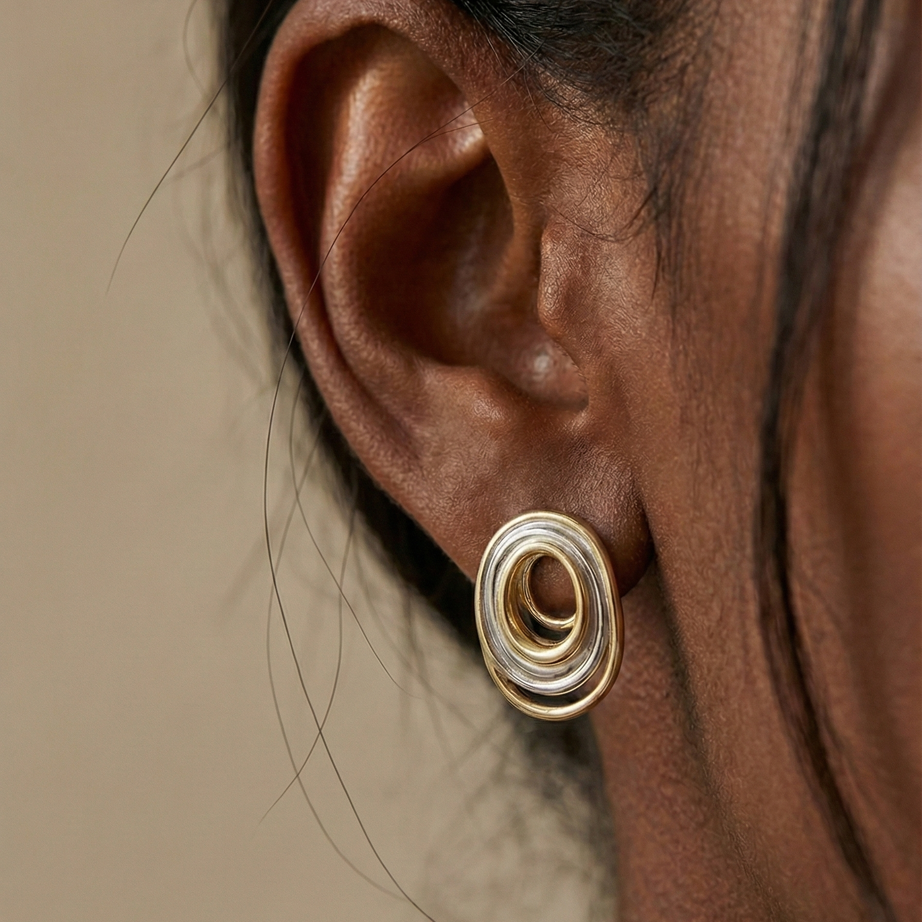 Ùsó Studs gold and silver mixed metal earring worn on ear in editorial close-up – flat back hypoallergenic spiral oval stud earrings in modern two tone stainless steel
