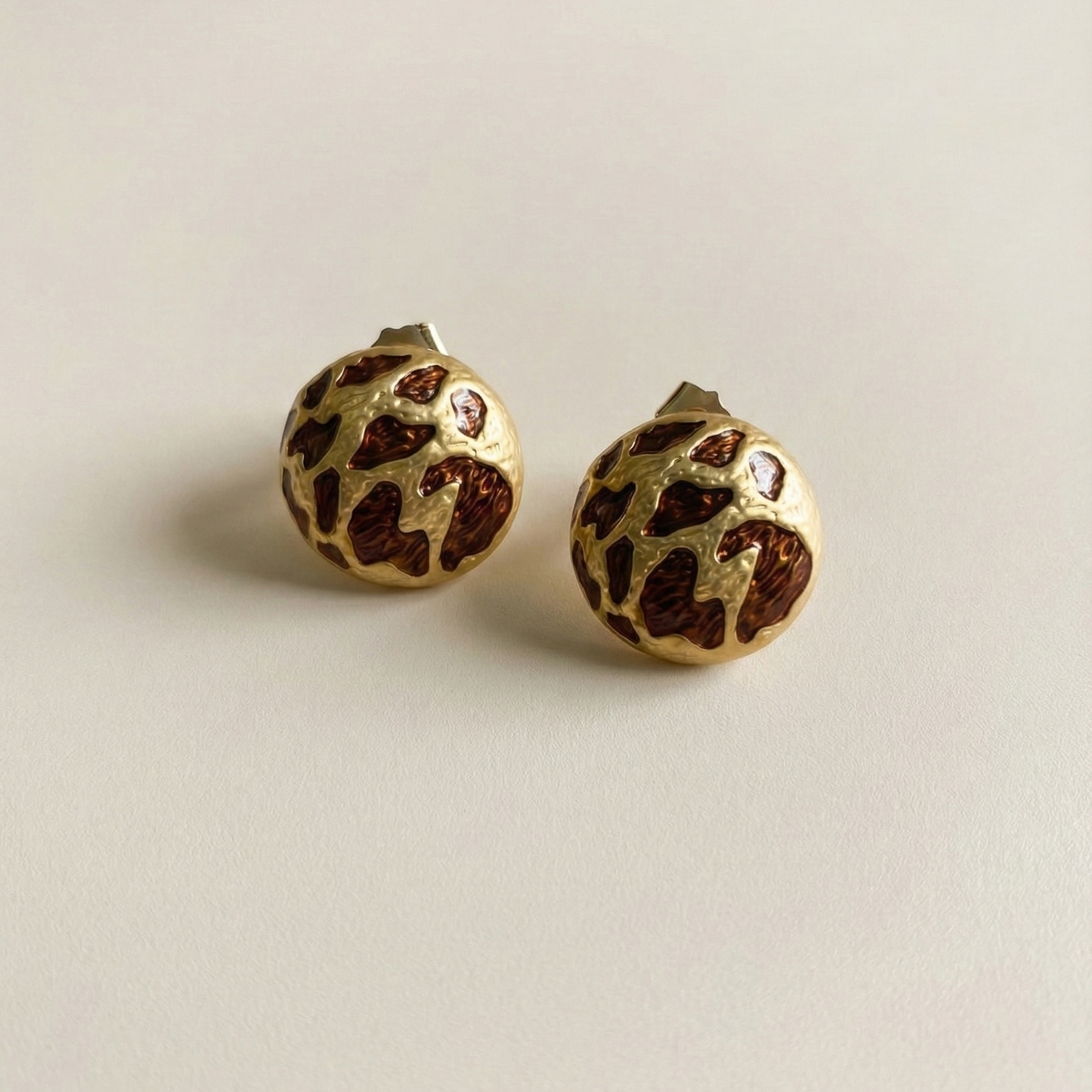 Zola Studs gold leopard print dome stud earrings flat lay on cream background – hypoallergenic tarnish free stainless steel animal print earrings that don't tarnish