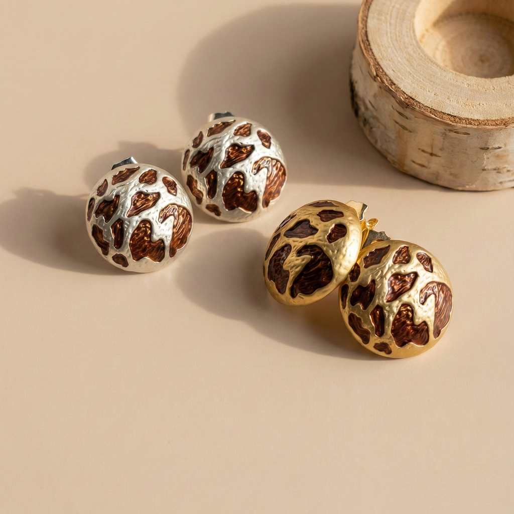 Zola Studs leopard print dome stud earrings shown in gold and silver finishes side by side with wooden prop – hypoallergenic stainless steel animal print stud earrings that don't tarnish