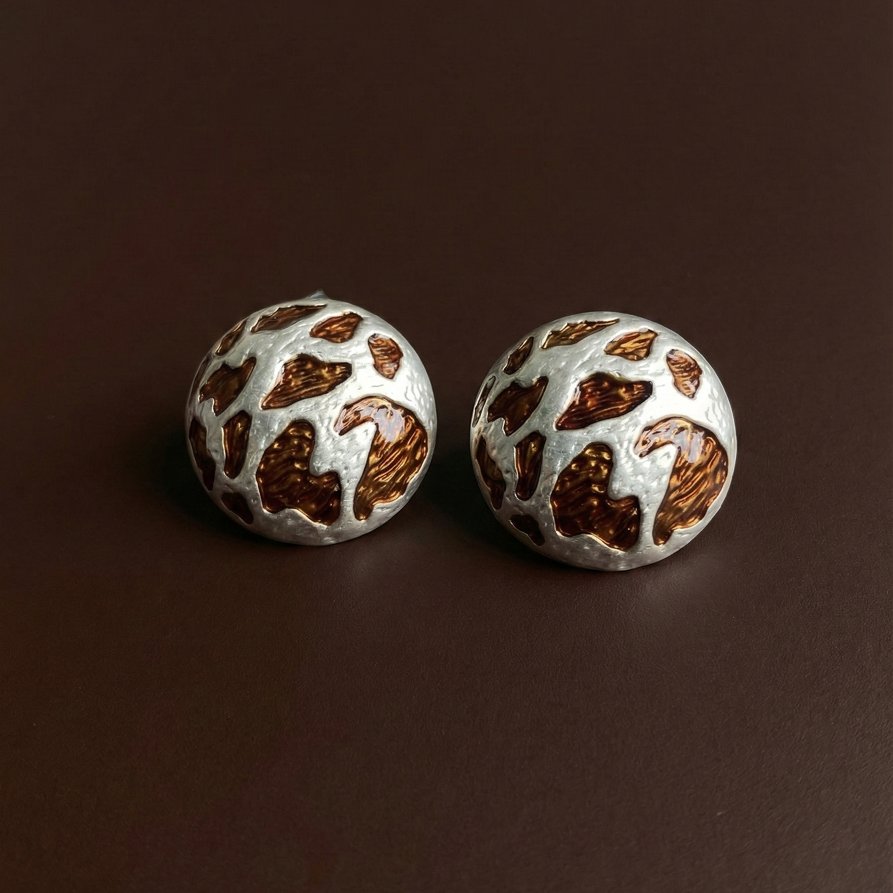 Zola Studs silver leopard print dome stud earrings flat lay on deep brown background – waterproof tarnish free stainless steel animal print earrings for sensitive ears